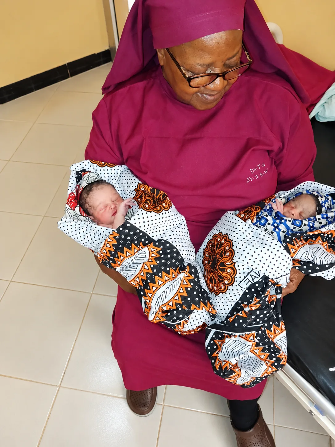 A sister holding newborn twins at the health centre